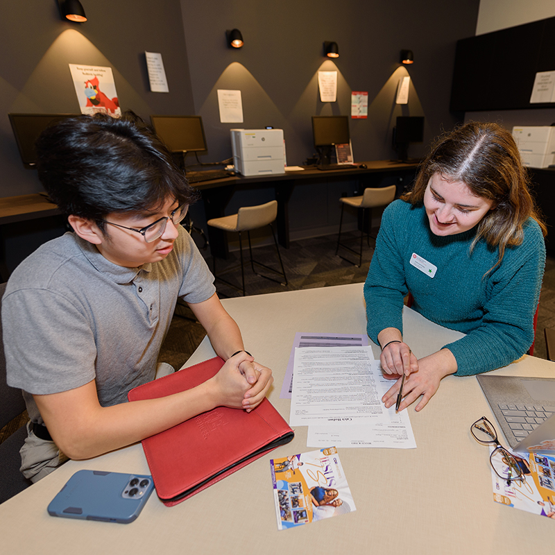 Student and advisor talking and looking into papers.